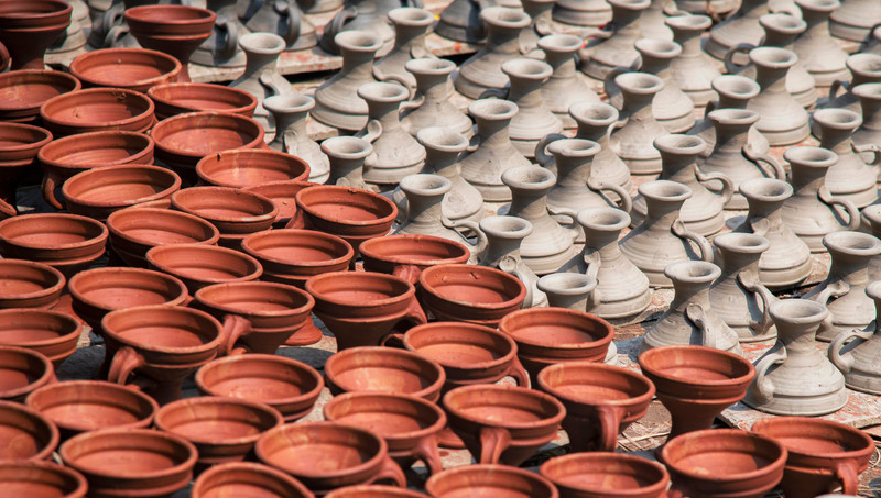Rows of clay diyas drying in the sun.