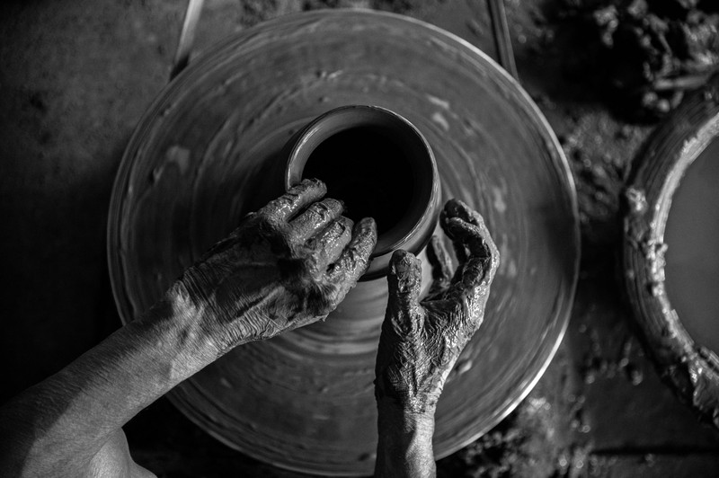 Hands centring clay on the wheel, black and white.
