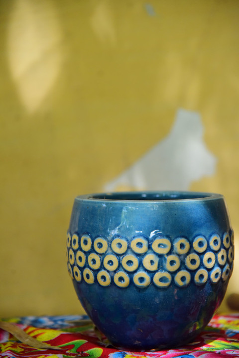 A blue ceramic pot with a circle pattern on yellow.