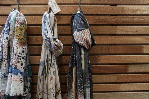 Printed stoles hanging on a wooden wall.