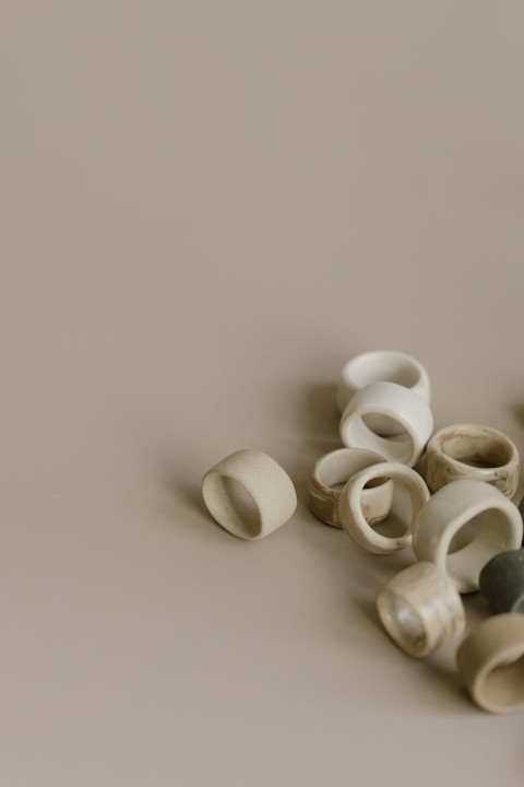 Cream ceramic rings on a sand background.