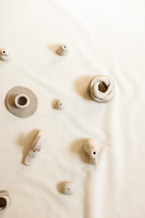 Small clay incense holders scattered on cream linen.