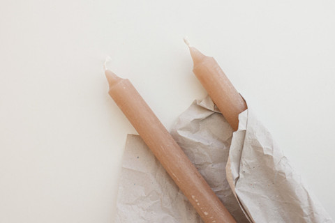 Two blush tapers wrapped in crumpled paper.
