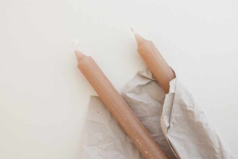 Two blush tapers wrapped in crumpled paper.