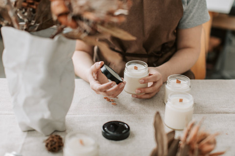 A candle maker pouring wax into a jar.