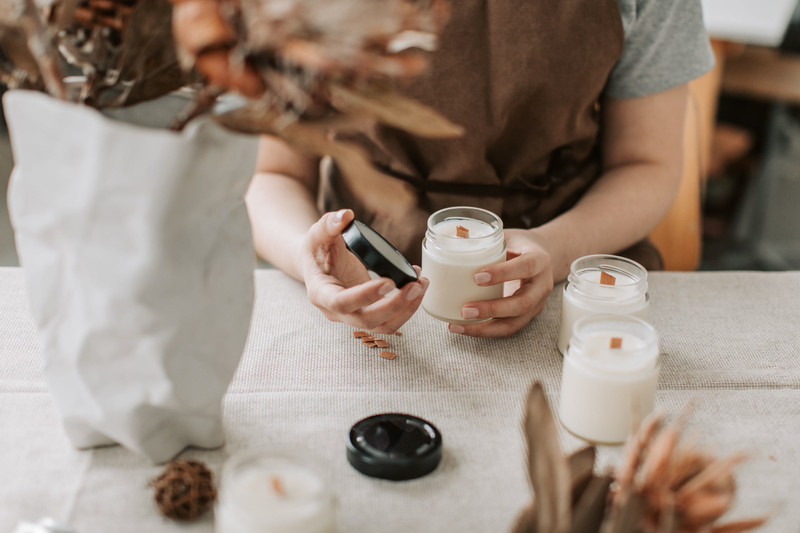 A candle maker pouring wax into a jar.