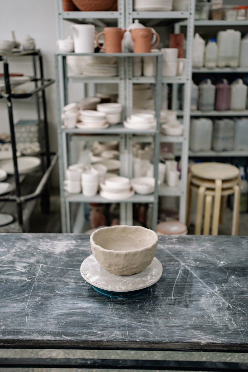 A pottery studio with a bowl drying on the bench.