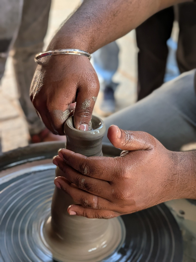 A potter raising a pot on the wheel.