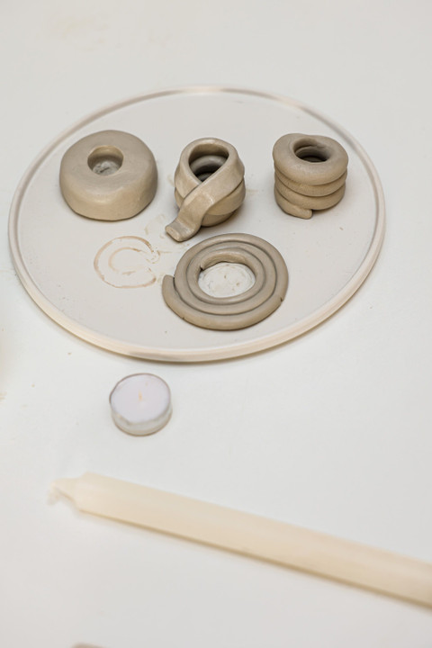 Clay candle holders on a white platter with a taper.