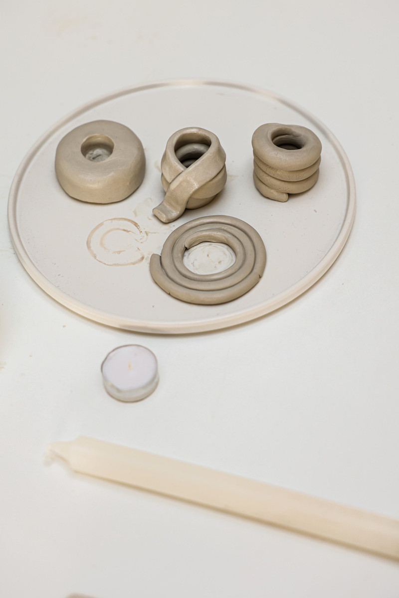 Clay candle holders on a white platter with a taper.